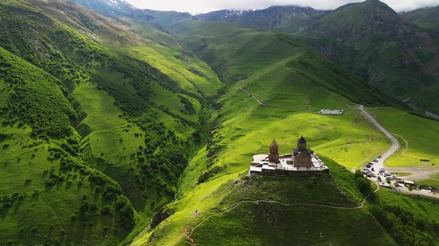 Cinematic 4K ProRes 422 aerial fly-by of Gergeti Trinity Church. Drone descent towards a mountain river in Kazbegi, Georgia.
