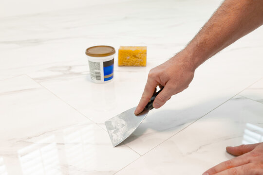 Applying grout on ceramic tile floor using putty knife during installation