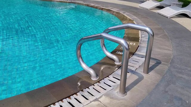 Swimming pool with metal ladder and clear blue water, featuring modern poolside design and relaxing resort atmosphere in a clean outdoor leisure setting.