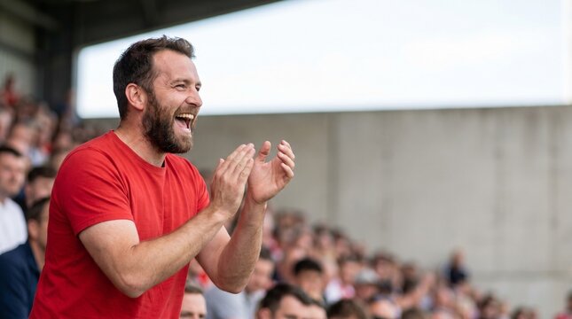 Excited man in red shirt clapping at a sports event