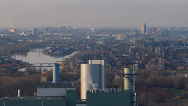 Aerial view of the Vattenfall Elektriciteitscentrale Diemen power plant with smoking chimneys overlooking the urban skyline and waterways in Diemen, Noord-Holland, Netherlands.