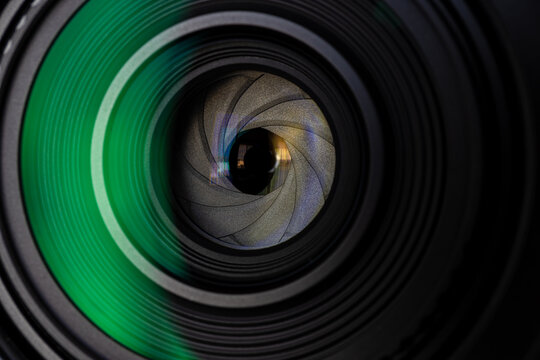 Close up of camera lens aperture blades with green lens flare reflection,Macro,Extreme close-up macro shot of a professional camera lens showing the mechanical aperture diaphragm blades and internal.