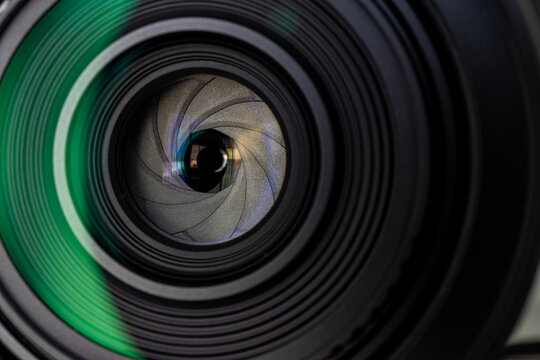 Close up of camera lens aperture blades with green lens flare reflection,Macro,Extreme close-up macro shot of a professional camera lens showing the mechanical aperture diaphragm blades and internal.