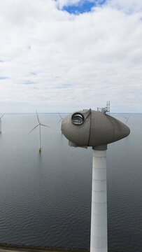 Aerial view of the Westermeerdijk wind farm nacelle with an open maintenance hatch overlooking the IJsselmeer under a cloudy sky in Espel, Flevoland, Netherlands.
