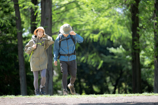 新緑の春の森の中を歩く夫婦のアウトドア、登山やトレッキングなどの運動イメージ全身