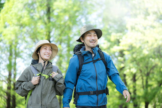 新緑の春の森の中を歩く夫婦のアウトドア、登山やトレッキングなどの運動イメージ上半身の笑顔のクローズアップ