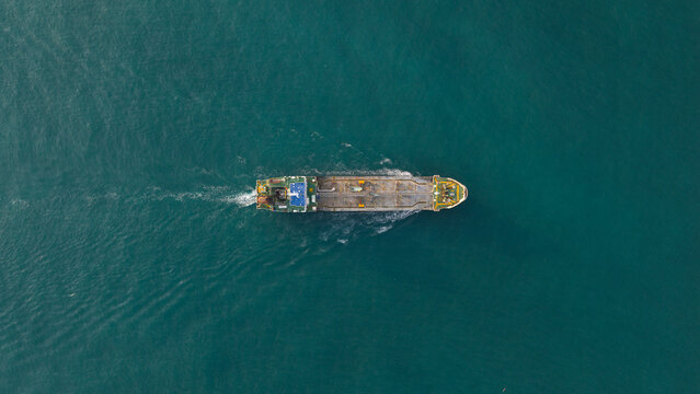 Aerial view of a cargo ship near the PTTLNG Nong Fab LMPT2 facility cruising through turquoise waters in Tambon Map Ta Phut, Chang Wat Rayong, Thailand.