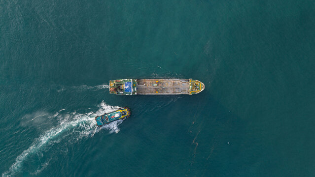 Aerial view of an industrial tanker and a support vessel navigating through deep turquoise waters near the PTTLNG Nong Fab LMPT2 in Tambon Map Ta Phut, Chang Wat Rayong, Thailand.