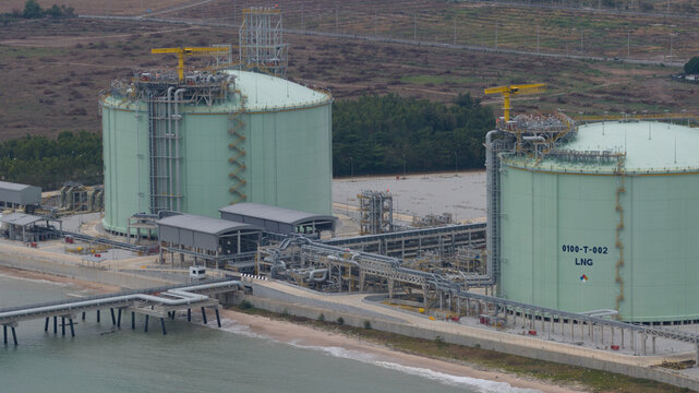 Aerial view of the PTTLNG Nong Fab LMPT2 terminal featuring large green LNG storage tanks and industrial infrastructure along the coast in Tambon Map Ta Phut, Chang Wat Rayong, Thailand.