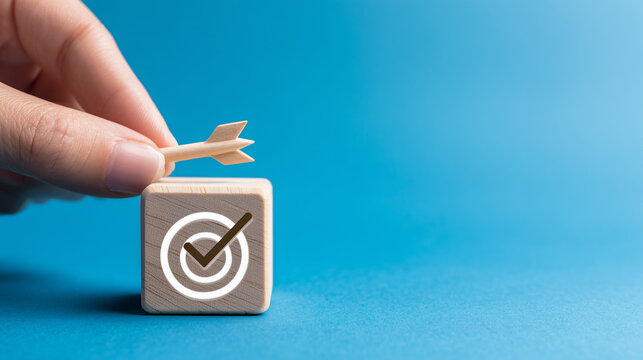 hand pushing wooden blocks with a checkmark icon towards a goal target on a blue background.