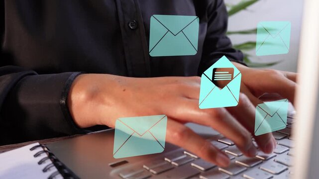 Hands type on laptop with floating email icons. Scene implies professional email management or online work