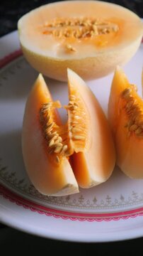 Slices of fresh sweet muskmelon with seeds on a white plate