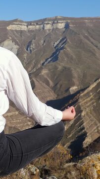 Woman Meditating On Mountain Cliff In Lotus Pose With Valley Panorama, Wearing White Shirt And Black Leggings, Hands In Mudra, Sunrise Light, Calm Mindful Retreat, Outdoor Wellness
