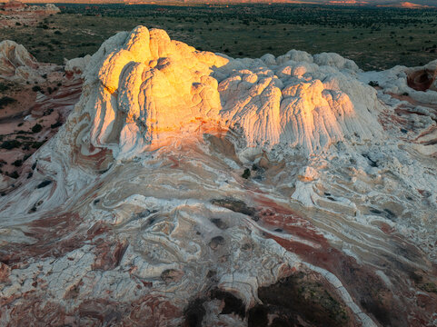 Aerial view of White Pocket rock formations with brain-like textures and swirling sandstone under golden hour light in Coconino County, Arizona, United States.