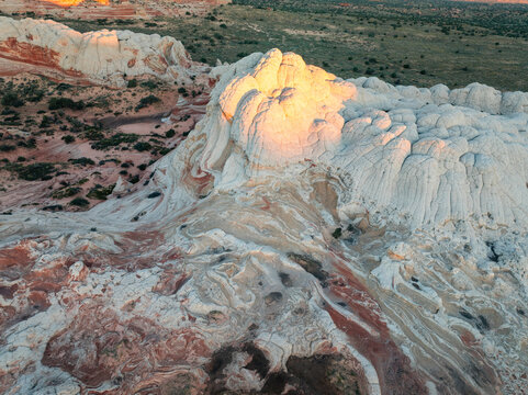 Aerial view of the unique swirling sandstone formations and brain-like rock textures of White Pocket under golden hour light in Coconino County, Arizona, United States.