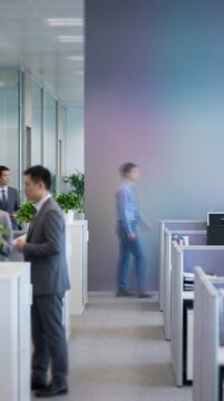 Business people walking past stationary man in office corridor, concept of disconnection and silent quitting in workplace