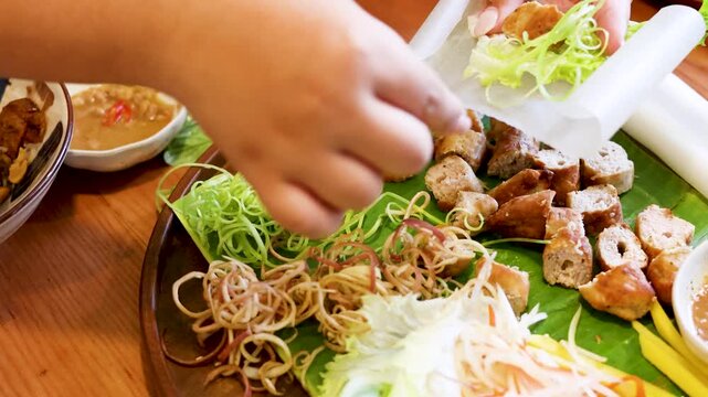 Hands Assembling Vietnamese Nem Nuong Spring Rolls with Fresh Herbs