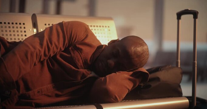 Exhausted by Waiting For Flight Man Sleeping on Airport Chairs. in Quiet Moment at Busy International Terminal, African American Male Finds Way to Nap on Hard Seating. Concept of Traveler Lifestyle.