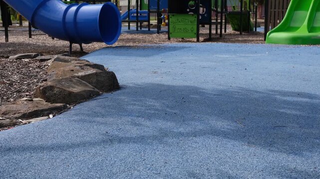 Blue rubber softfall safety surface at a children's playground in Australia. The wet pour rubber surfacing provides impact absorption and safety compliance for fall zones&nbsp;in a suburban Melbourne park.