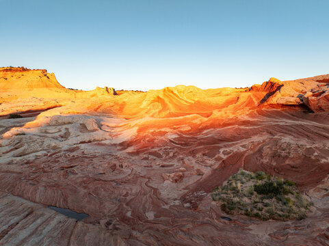 Aerial view of White Pocket rock formations with swirling sandstone patterns and golden hour light in Coconino County, Arizona, United States.