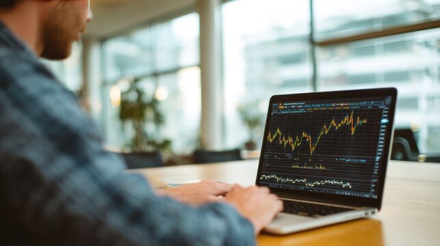 Investment Analysis: A focused individual intently analyzes financial data on a laptop, charting the course of the market with precision.