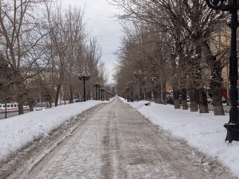 March 22 2026 Barnaul Russia alley on Leninsky Avenue opposite Polytechnic University covered in snow cold early spring cityscape urban environment and winter atmosphere.
