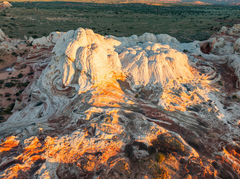 Aerial view of the unique White Pocket rock formations with swirling sandstone patterns and golden hour light in Coconino County, Arizona, United States.