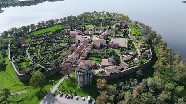 Drone aerial view of Granadilla, a medieval walled village on an island in a reservoir in Extremadura, Spain, showing detailed urban layout, traditional houses, narrow streets and fortified walls.