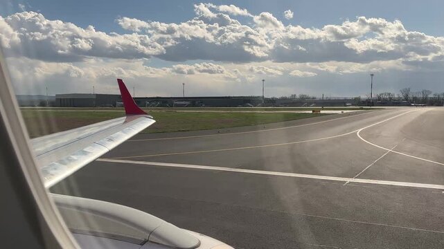 View from an airplane window during takeoff from Iași International Airport, Romania. The aircraft wing and runway are visible as the plane accelerates, with airport buildings and sky