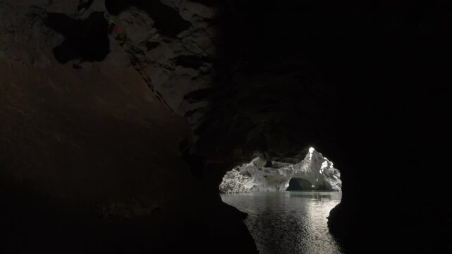 A cave is lit up in a second chamber by a hole in the ceiling and the water and white limestone can be seen clearly as sunlight lights it up.