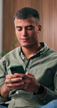 Man, relax and typing on couch with phone, check social media post and online dating site notification. Happy, person and scroll in home with tech, mobile app and connectivity for text message alert.