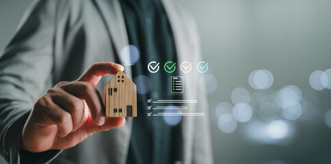 Obraz na płótnie Canvas Hand holding wooden house model with quality checklist and approval icons, real estate investment and property evaluation concept, home insurance, mortgage approval and housing security assurance