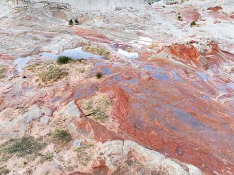 Aerial view of the unique swirling sandstone formations and water-filled potholes of White Pocket under soft light in Coconino County, Arizona, United States.