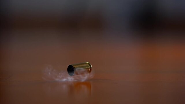 Bullet shell casing falling to wooden surface in slow motion. Fired brass casing bouncing after shot, Slow motion