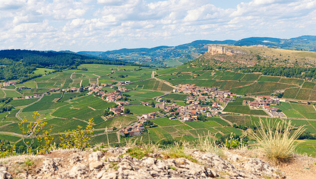 High angle panorama of Solutre-Pouilly village and vineyards from the Rock of Solutre, Burgundy, France. Iconic limestone escarpment landscape in M&acirc;connais wine region under summer sky.