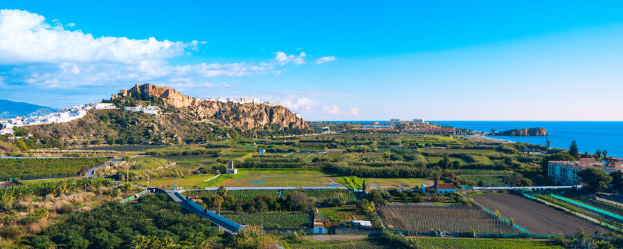 Panoramic view of Salobre&ntilde;a white village and Moorish castle on a rock, Granada, Spain. Agricultural fields and Mediterranean sea landscape in Andalusia under blue sky.
