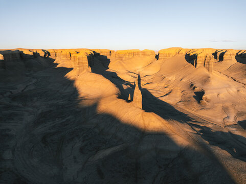 Aerial view of the unique badlands and rock formations under golden hour light in Hanksville, Utah, United States.