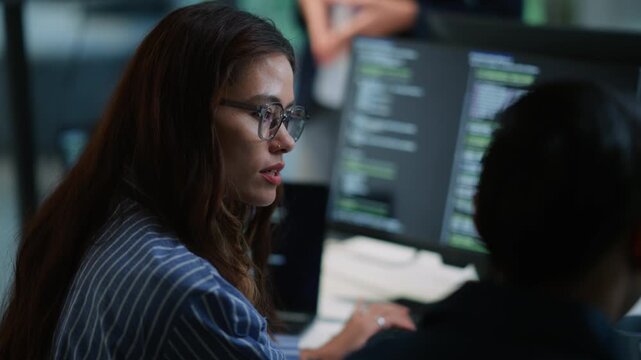 Mentor explaining work to new colleague in tech company, multiple screens on desk, teamwork, onboarding, collaboration, training, digital workplace, modern office environment, innovation