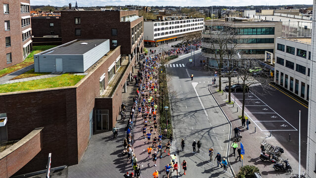 Aerial drone view of people running half marathon Venloop race in city, crowd runners on road racing sport competition, top-down view of athletes and spectators, Venlo, the Netherlands