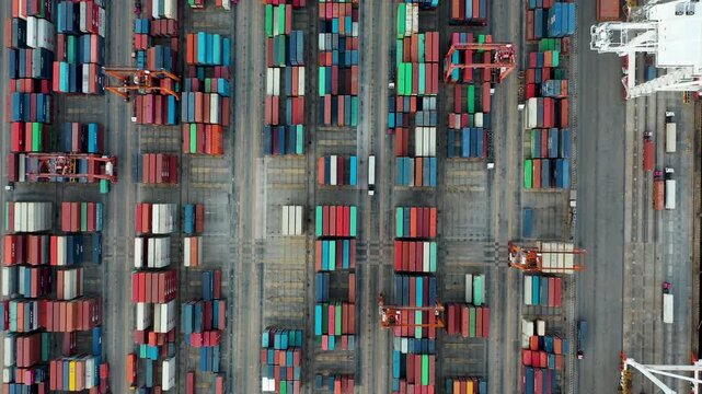 Aerial Top view of a large cargo ship loading and unloading containers at a deep-sea port. This aerial scene highlights global logistics, international trade, and maritime transportation hubs.