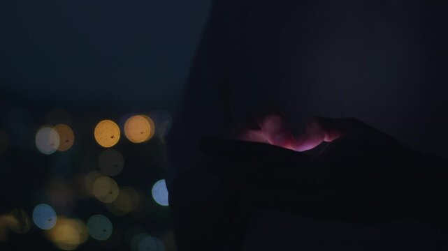 Smartphone glow in dark night shows hand using mobile device for private communication and technology lifestyle. Close up touch screen at night suggests privacy security focus and modern digital life