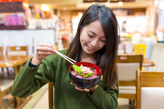 Woman enjoying tekka don rice bowl in japanese restaurant in japan