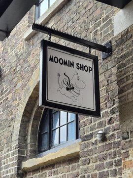 London UK 05.07.2025 Moomin Shop sign on brick building facade with cartoon character illustration hanging storefront signage in urban street setting
