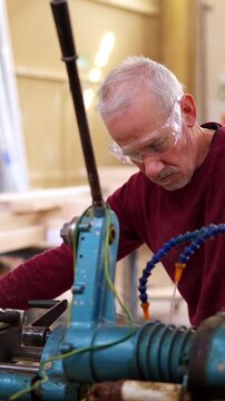 Senior craftsman operating an industrial wood lathe machine