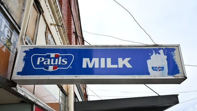 Blue Pauls Milk sign hanging outside an old milk bar, featuring the dairy brand's logo