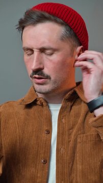 A man interacts with wireless headphones, demonstrating a broken, non-functional device. There is no connection