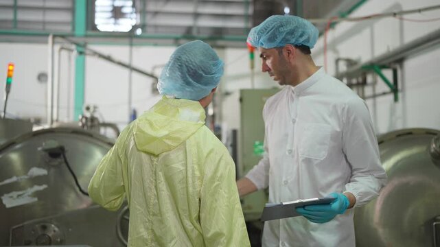 Precision in Production: Two professionals engage in detailed discussion within an industrial setting. Meticulous examination of industrial machinery and adherence to strict operational protocols.