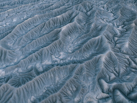 Aerial view of Factory Butte badlands showing intricate eroded ridges and deep valleys under soft light in Wayne County, Utah, United States.