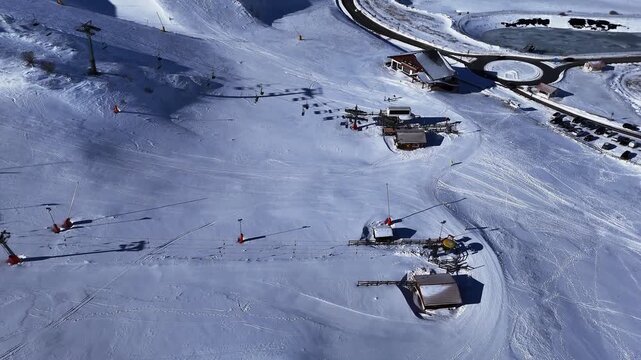 Drone aerial video of ski resort with ski lifts and skiers on snowy slope in Abruzzo, Italy