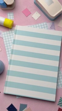 Pink desk with blue striped journal and craft supplies
